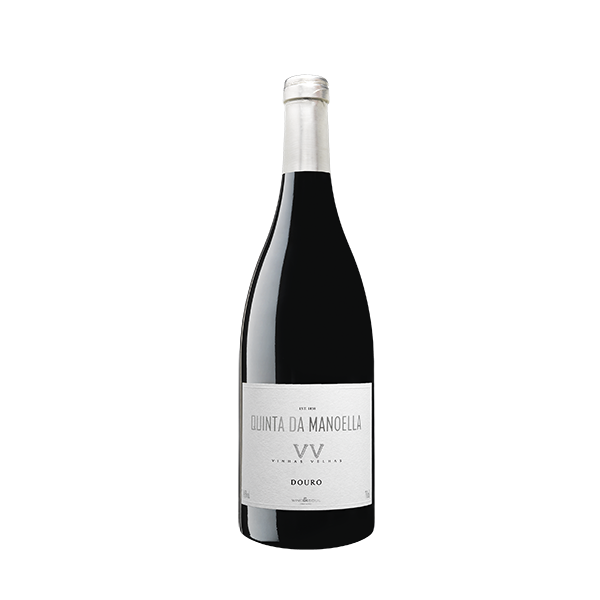 Taça de vinho com garrafa de Manoella Vinhas Velhas da Wine and Soul sobre mesa de madeira.
