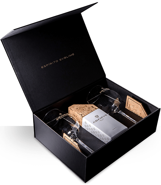Conjunto de gin Adamvs com dois copos de destilados, elegante embalagem e detalhes do produto visíveis na imagem.