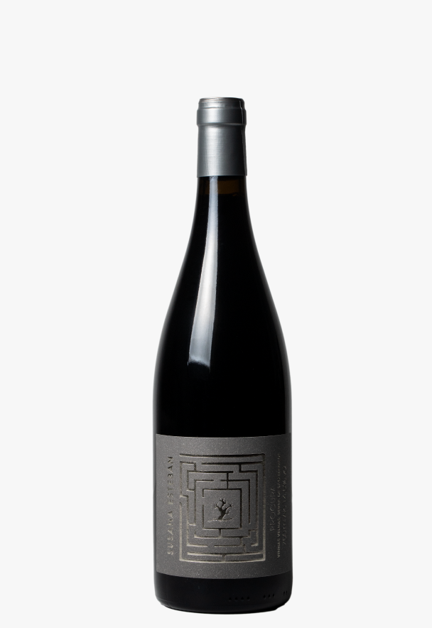 Taça de vinho tinto Susana Esteban Procura, mostrando a cor rubi e detalhes do rótulo na garrafa.
