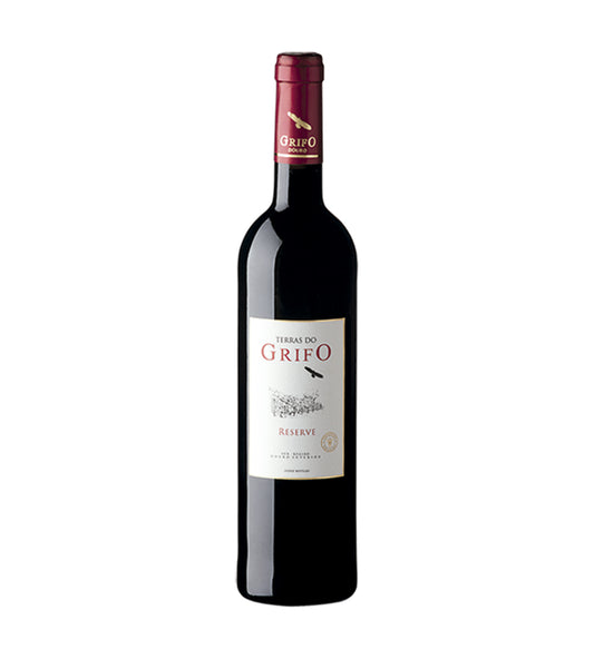 Taça de vinho tinto Reserva Terras do Grifo, produzido pela ROZÈS, SA, com garrafa de vinho tinto na mesa.