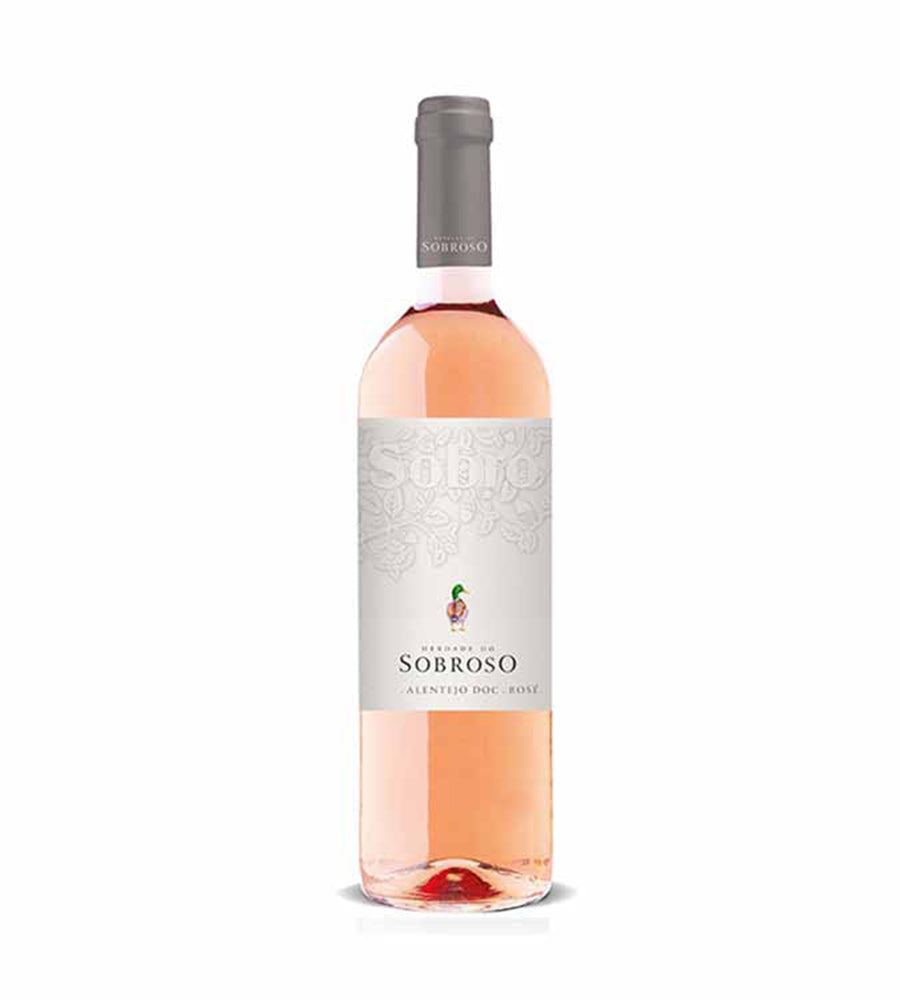 Taça de vinho rosé Herdade do Sobroso Sobro Rosé, com garrafa ao fundo, em ambiente elegante e bem iluminado.