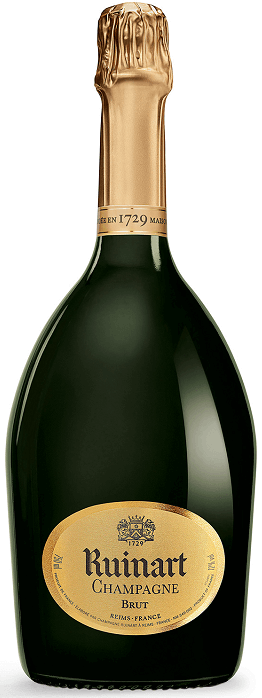 Taça de champagne Ruinart Brut com garrafa de champagne Ruinart ao fundo, destaque para o rótulo da garrafa.