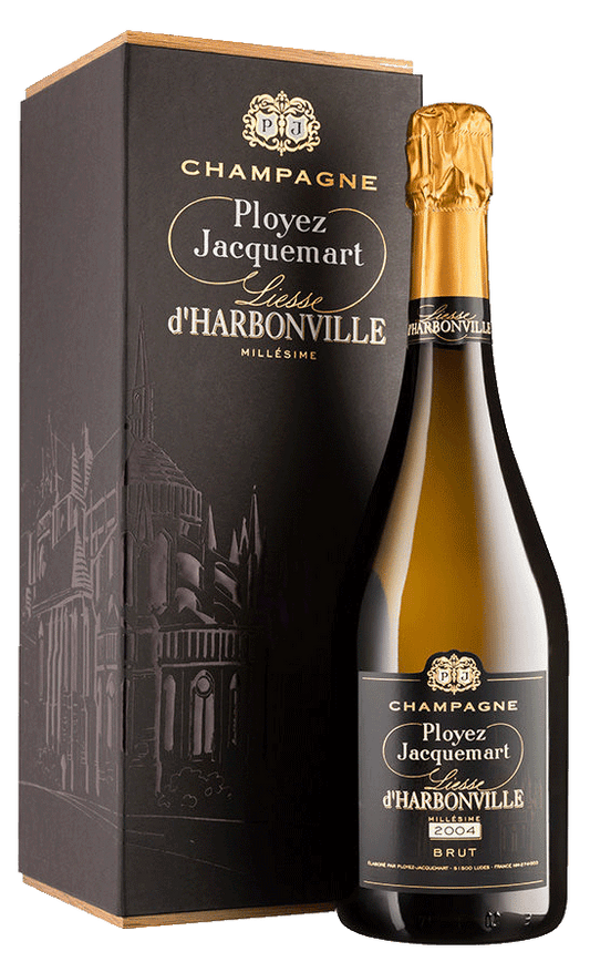 Taça de Champagne Ployez-Jacquemart Liesse D'Harbonville 2004 Brut com garrafa de champagne ao fundo.
