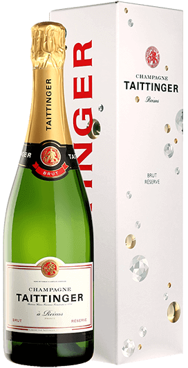 Taça de champagne Taittinger Reserve Brut com garrafa de Taittinger Reserve Brut ao fundo, destaque para rótulo e bolhas na taça