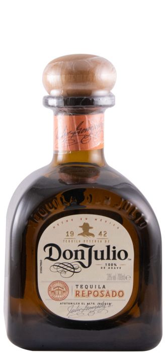 Taça de tequila Don Julio Reposado com garrafa de destilados na mesa, destaque para a embalagem e o líquido dourado.