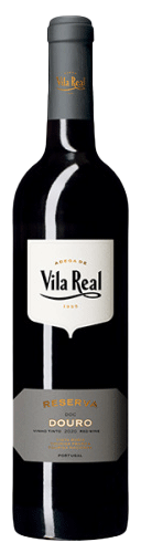 Taça de vinho tinto Vila Real Reserva 2022 da Adega Cooperativa de Vila Real, com garrafa ao fundo.