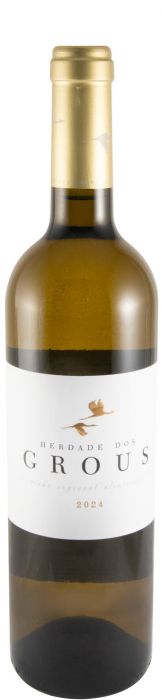Taça de vinho branco Herdade Dos Grous Branco da Monte do Trevo, garrafa de vinho em destaque sobre mesa.