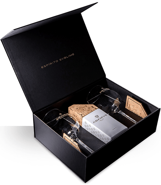 Conjunto de gin Adamvs com dois copos de destilados, elegante embalagem e detalhes do produto visíveis na imagem.
