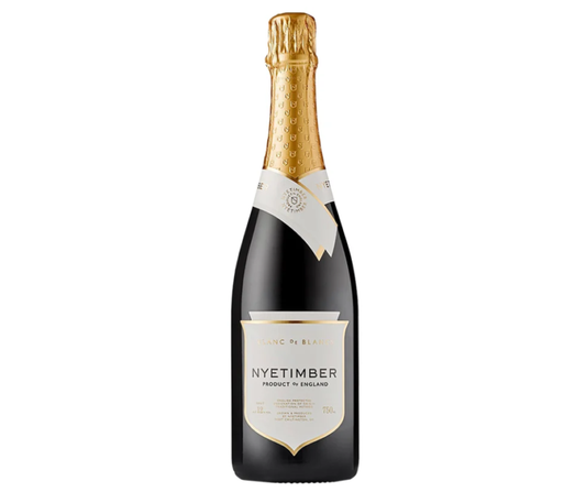 Espumante Nyetimber Blanc De Blancs Brut na taça, com garrafa ao fundo, destaque para a bebida espumante de luxo.